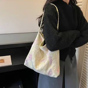 Elegant model carrying a Chinese style large capacity shoulder bag with pink floral embroidery.