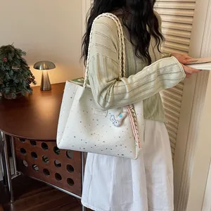 Vue détaillée d'un sac cabas blanc à motif étoilé avec lanières tressées et un charm