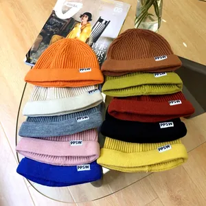 Close-up of colorful children's knit beanies with PPSW label on glass table