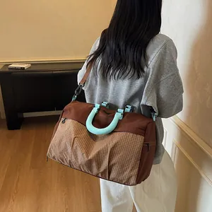 Model carrying a brown and blue checkered weekend bag over the shoulder