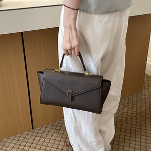 Detailed macro view of an elegant dark brown textured handbag with gold hardware