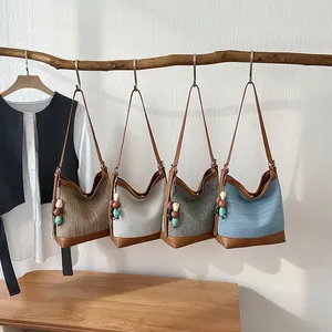 Selection of four stylish woven summer bucket bags for women hanging on a natural wooden branch