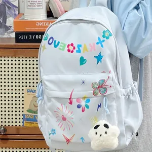 Detail of light blue backpack with colorful graffiti prints and star plush charm