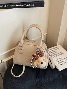 Elegant beige Boston handbag with crossbody strap and cute plush teddy bear charm detail