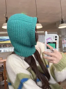 Detailed side view of a cozy teal green knitted balaclava hooded scarf on a model