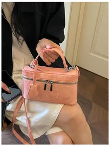 Detailed view of a small pink box vanity handbag held by a woman in a white dress