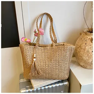 Sac cabas élégant en paille tressée avec pompon, présenté dans un cadre de vie chic