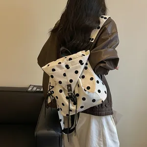 Close-up detail of the stylish white and black polka dot backpack with leather straps.