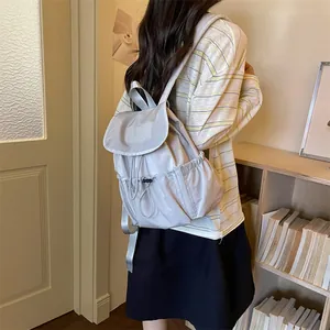 Detailed view of grey drawstring pleated backpack worn on back in lifestyle setting