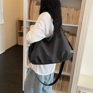 Vista lifestyle di una grande borsa da viaggio a scacchi nera indossata in una stanza