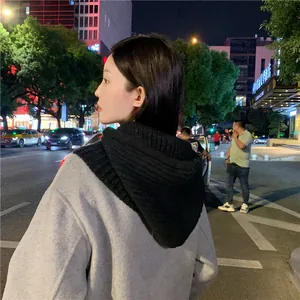Back view of a woman wearing a black knitted integrated hood scarf and shawl combo