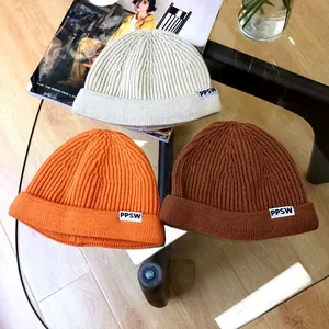 Detailed view of children's solid color knitted beanies with letter labels in three colors