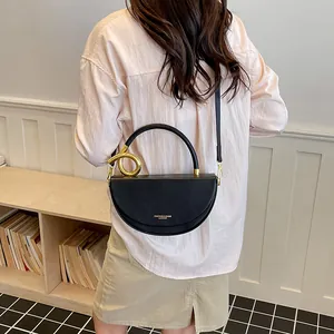 Rückansicht einer Frau mit einer stilvollen schwarzen Satteltasche mit goldenem Ringgriff