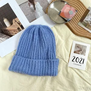 Detailed view of a soft blue chunky knit beanie hat presented in a cozy lifestyle setting