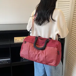 Large burgundy grid pattern travel bag shown worn as a shoulder bag for stylish commute