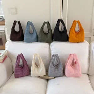 Mehrfarbige Kollektion von Strick-Eimertaschen mit Mikrokaro-Muster auf weißem Sofa