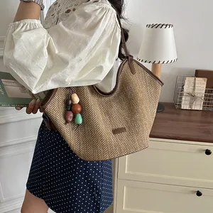 Handmade straw woven tote bag with colorful wooden beads shown in a lifestyle setting