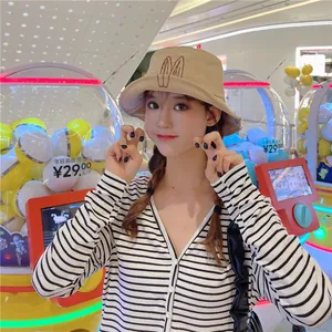 Young woman wearing a khaki bucket hat with cute rabbit ear embroidery in a bright mall