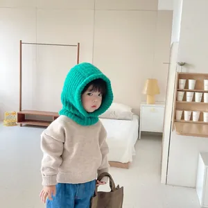Detailed shot of a toddler wearing a bright green knitted balaclava hood indoors