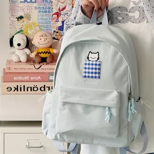 Detail view of light blue Japanese style student backpack with cat embroidery and checkered pocket
