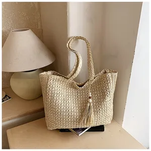 Sac cabas tissé en paille fait main avec pompon décoratif sur une table en bois clair
