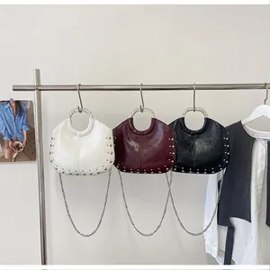 Three chic studded handbags with metal handles and chain straps shown on a display rack.