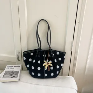 Stylish black and white polka dot canvas tote bag with a yellow palm tree charm accessory