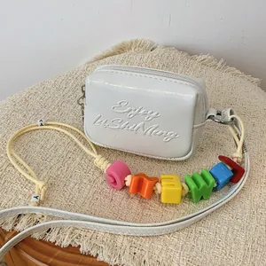 Detailed view of white mini square bag featuring colorful alphabet beads and embossed text