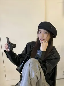Detail shot of a black washed denim beret on an Asian model with a retro camera prop.