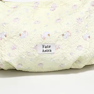 Close-up of a pale yellow quilted dumpling bag featuring a cute lamb pattern and brand label.
