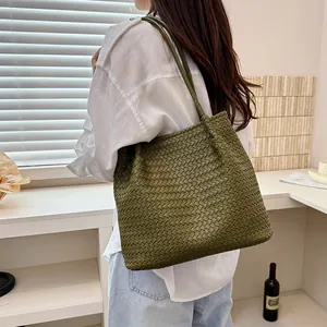 Large olive green woven tote bag with slim shoulder strap being worn by a model