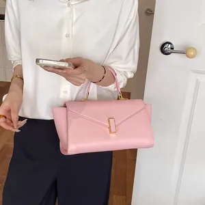 Close-up of stylish pink crossbody handbag with gold-tone clasp held by model