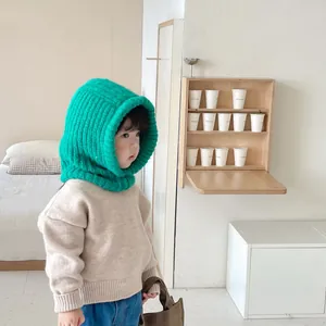 Toddler wearing a vibrant green knitted balaclava hood scarf in a cozy indoor room