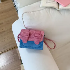 Stylish color-block crossbody bag in pink and blue resting on a cozy white sofa