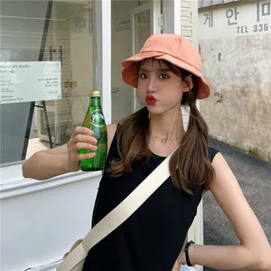 Coral orange ruffled brim bucket hat with elegant wavy edge design worn by Asian model outdoors.