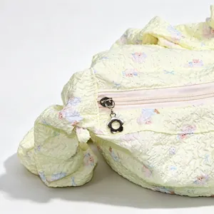 Close-up of seersucker dumpling bag showing flower zipper pull and cute bear pattern