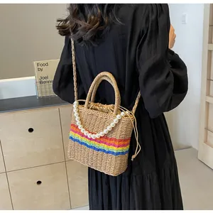 Handmade woven straw bucket bag with vibrant rainbow stripes and elegant pearl handle detail