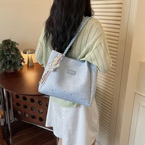 Détail d'un sac cabas bleu clair à motifs d'étoiles porté avec bandoulière tressée