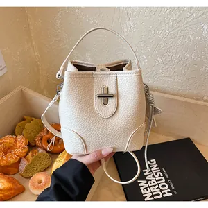 Détail d'un sac seau en cuir texturé crème avec fermeture à fermoir rotatif élégante
