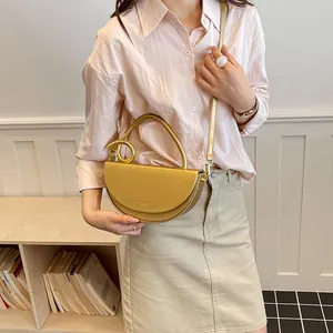 Goldene Vintage-Satteltasche für Damen, getragen von einem Model in lässiger Umgebung