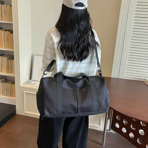Bolsa de viaje grande negra con lunares llevada por una modelo en un entorno de hogar