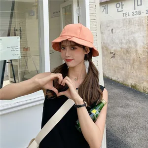 Close-up of orange lotus leaf edge bucket hat on model in outdoor street setting