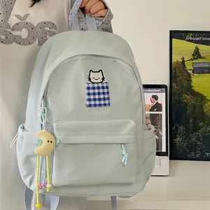 Detailed view of a light blue student backpack with cat embroidery and a moon charm