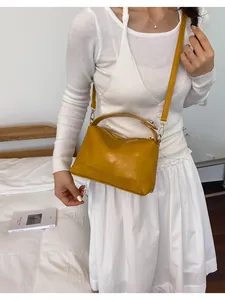 Gele retro Boston handtas gestyled met witte outfit in een gezellige binnenomgeving