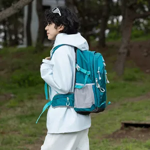 Detail view of teal waterproof hiking backpack worn by model in outdoor forest setting.