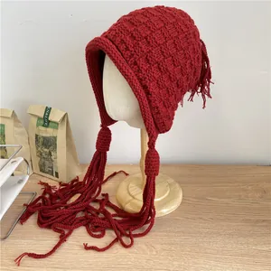 Handgemachte rote Strickmütze mit Ohrenklappen und langen Quasten für den Winter