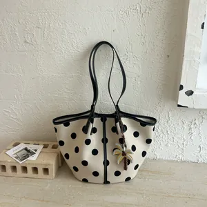 Detailed macro view of a cream polka dot tote bag featuring a decorative palm tree charm