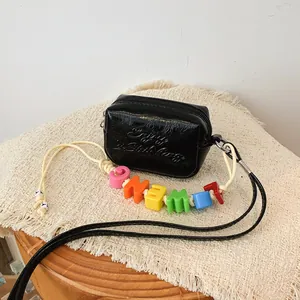 Detailed view of a black mini crossbody bag with colorful letter beads on the strap