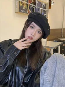 Stylish young woman wearing a vintage black denim beret while posing in a trendy cafe setting