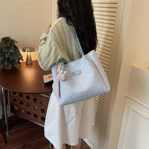 Femme portant un sac cabas bleu clair à étoiles avec breloque lapin
